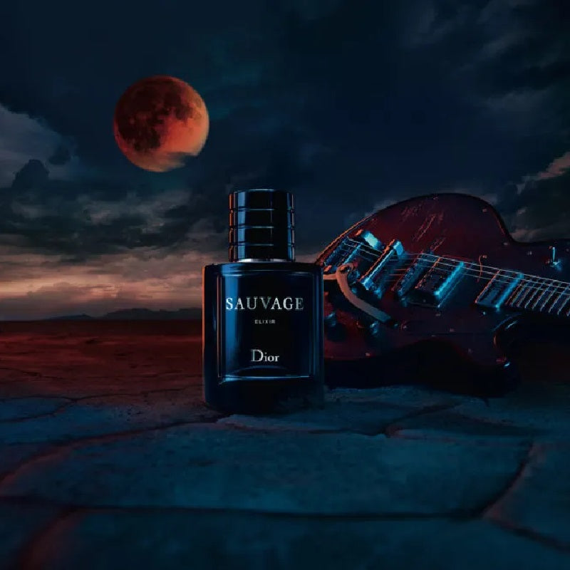 Dior Sauvage Elixir perfume bottle on a deep blue background and behind a guitar and the moon