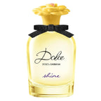 A bottle of Dolce Shine Eau de Parfum by Dolce & Gabbana with a clear yellow liquid visible and a black bow with a yellow flower on the cap.