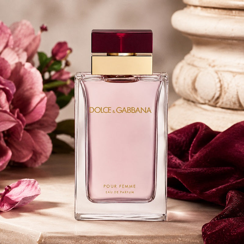 Dolce & Gabbana perfume bottle with pink flowers and a decorative stone object in the background