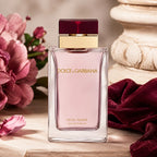Dolce & Gabbana perfume bottle with pink flowers and a decorative stone object in the background