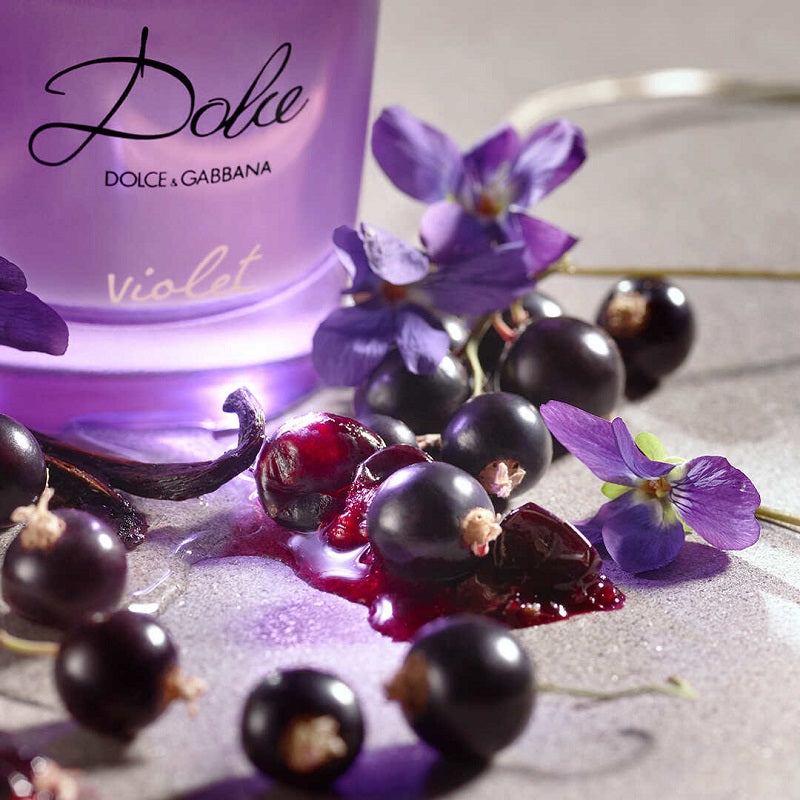 A purple bottle of Dolce Violet perfume by Dolce Gabbana with a floral design and a black grapes ad violets pictured