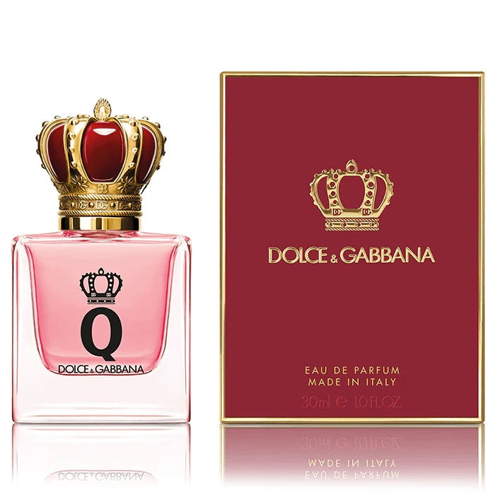 A product image featuring Dolce Q-Queen Eau de Parfum by Dolce Gabbana, with a glass bottle in pink hue topped with a golden crown and a matching red label, alongside the perfume box with the brand's logo.