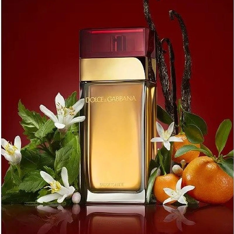 Dolce & Gabbana perfume bottle with flowers and oranges on a red background