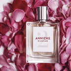 Perfume bottle labeled 'Annicke by Eight & Bob' surrounded by pink flowers