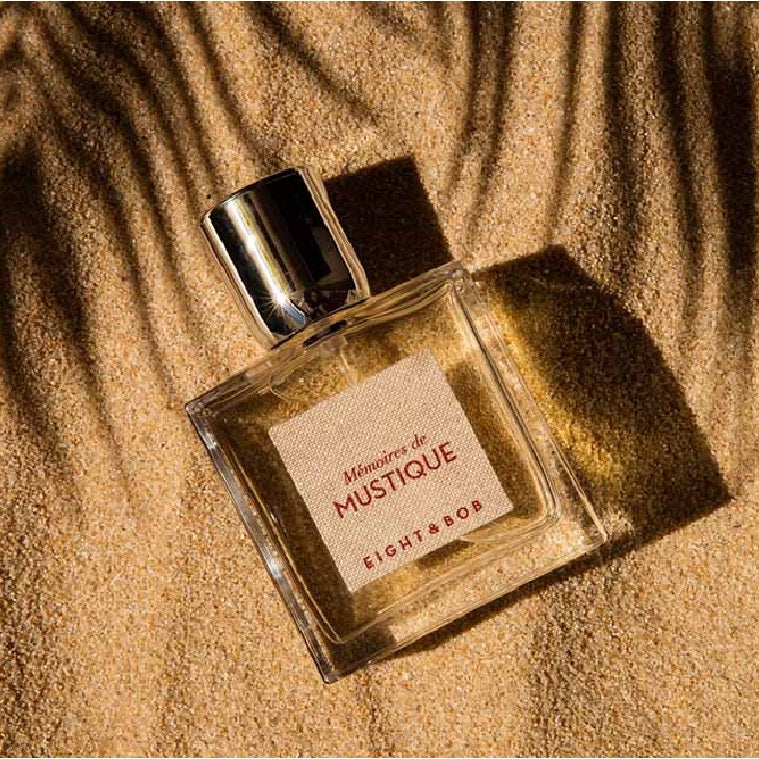 Perfume bottle labeled 'Memoires de Mustique' by Eight & Bob on sand