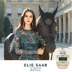 Woman in a blue dress standing next to a horse with an Elie Saab perfume bottle in the foreground.