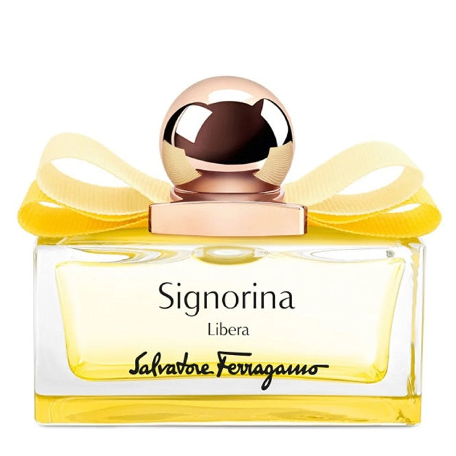 A bottle of Signorina Libera Eau de Parfum by Salvatore Ferragamo with a clear yellow liquid visible, a gold-colored cap, and a yellow ribbon decoration on the lid.