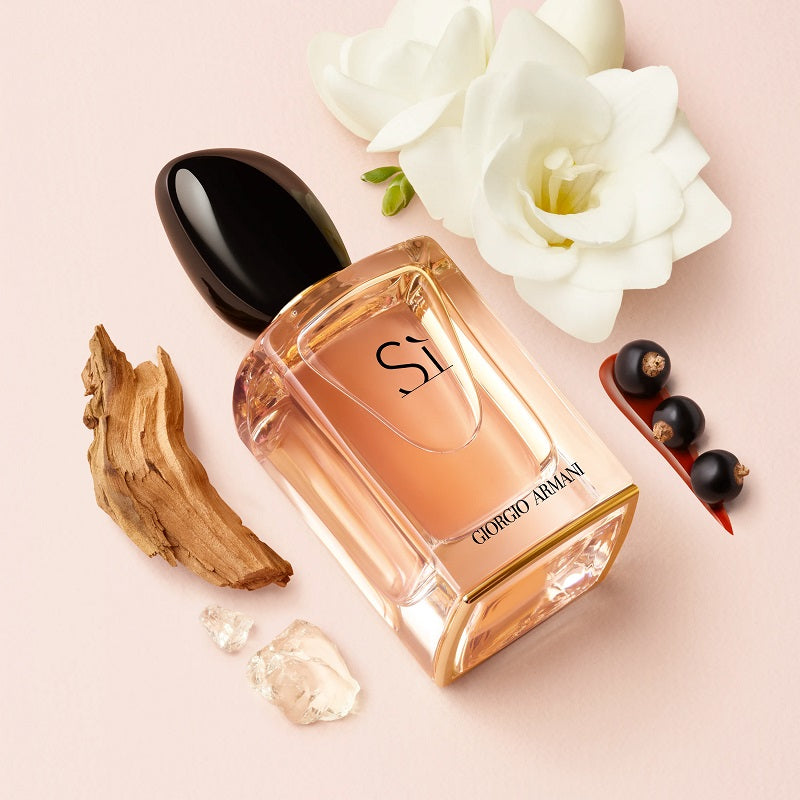 Armani Sì bottle on plain white background surrounded by white roses