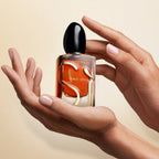 Hand holding a Giorgio Armani perfume bottle against a beige background