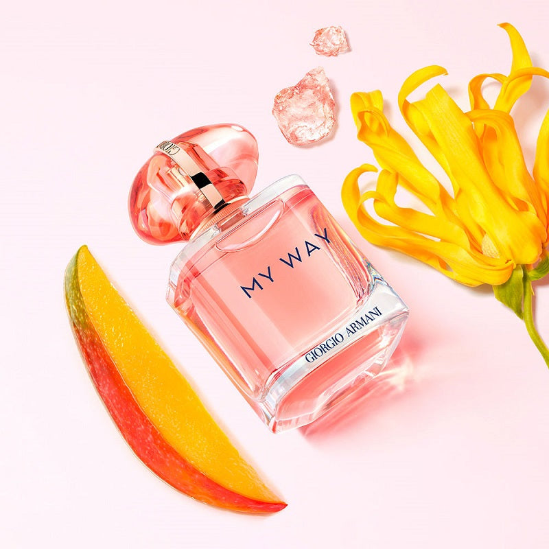 Giorgio Armani 'My Way' perfume bottle with mango slices and flowers on a light pink background