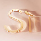 Gold hoop earrings on a soft pink background