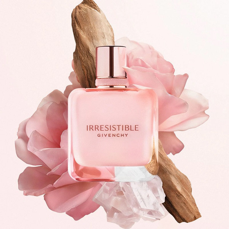 Givenchy Irresistible perfume bottle surrounded by pink flowers on a light pink background