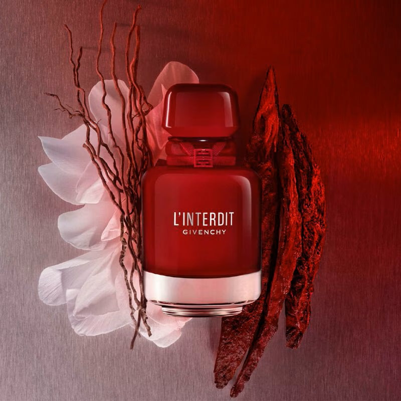 Red Givenchy L'Interdit perfume bottle with floral and branch elements on a red background