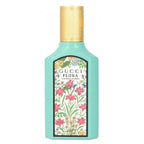 A turquoise bottle of Gucci Flora Gorgeous Jasmine Eau de Parfum with a floral label and a gold cap.
