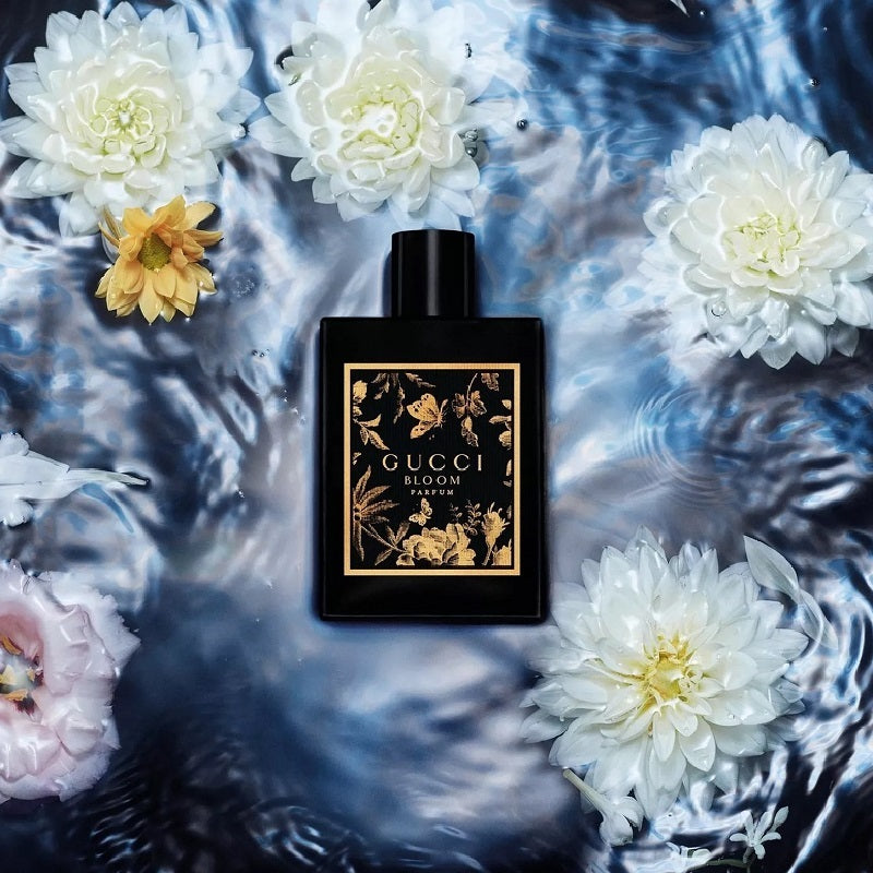 Black Gucci Bloom perfume bottle surrounded by floating flowers on water