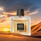 Perfume bottle labeled 'L'Homme Ideal Intense' against a desert sunset.