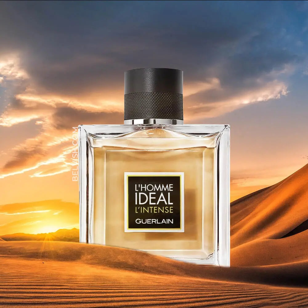 Perfume bottle labeled 'L'Homme Ideal Intense' against a desert sunset.
