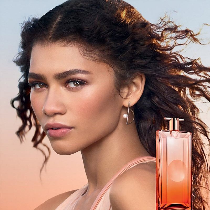 Woman with flowing hair and a perfume bottle in the foreground