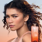 Woman with flowing hair and a perfume bottle in the foreground