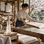 A woman makes washi paper in a Japanese workshop beside a bottle of L'Eau d'Issey Eau & Magnolia and magnolia blossoms.