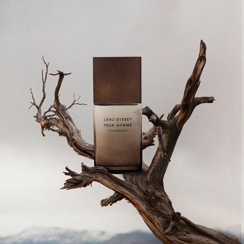 Perfume bottle labeled 'Leau Dissey Pour Homme' on a wooden branch against a light background
