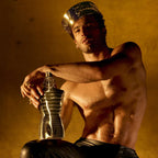 Model dressed as a king holding a large Factice of a bottle of le-male and wearing leather trousers