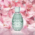 Perfume bottle with pink flowers in the background