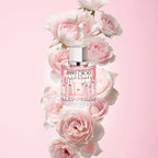 Perfume bottle surrounded by pink flowers on a pink background