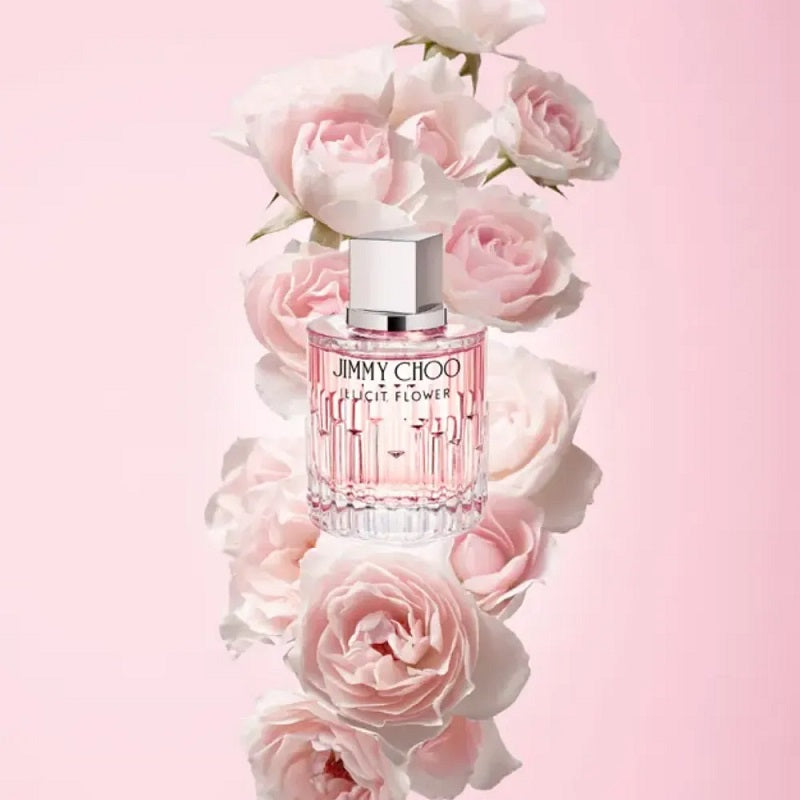 Perfume bottle surrounded by pink flowers on a pink background