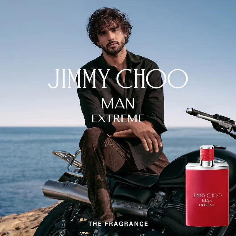 Man sitting on a motorcycle with Jimmy Choo Man Extreme fragrance bottle by the ocean.