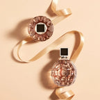 Perfume bottle with decorative ribbon on a beige background