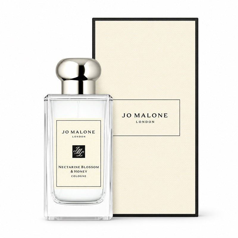 Jo Malone London Nectarine Blossom & Honey Cologne bottle in a clear glass rectangular bottle with a silver cap, shown next to its cream-colored textured packaging box on a white background.