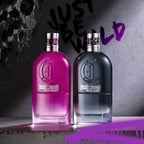 Two 'Just Cavalli Wild Heart' perfume bottles, one pink and one black, on a textured surface with a dark background.