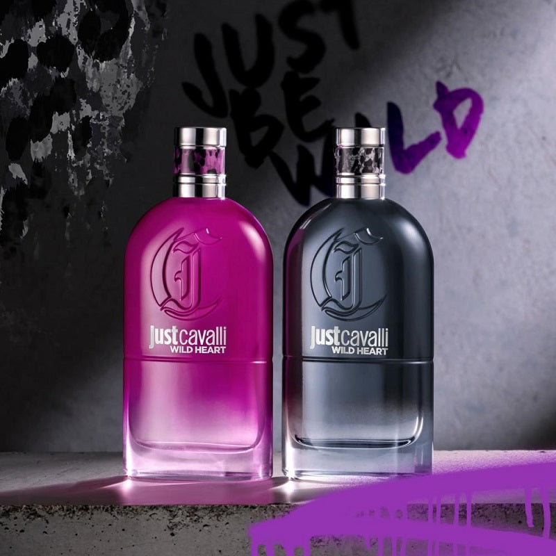 Two 'Just Cavalli Wild Heart' perfume bottles, one pink and one black, on a textured surface with a dark background.