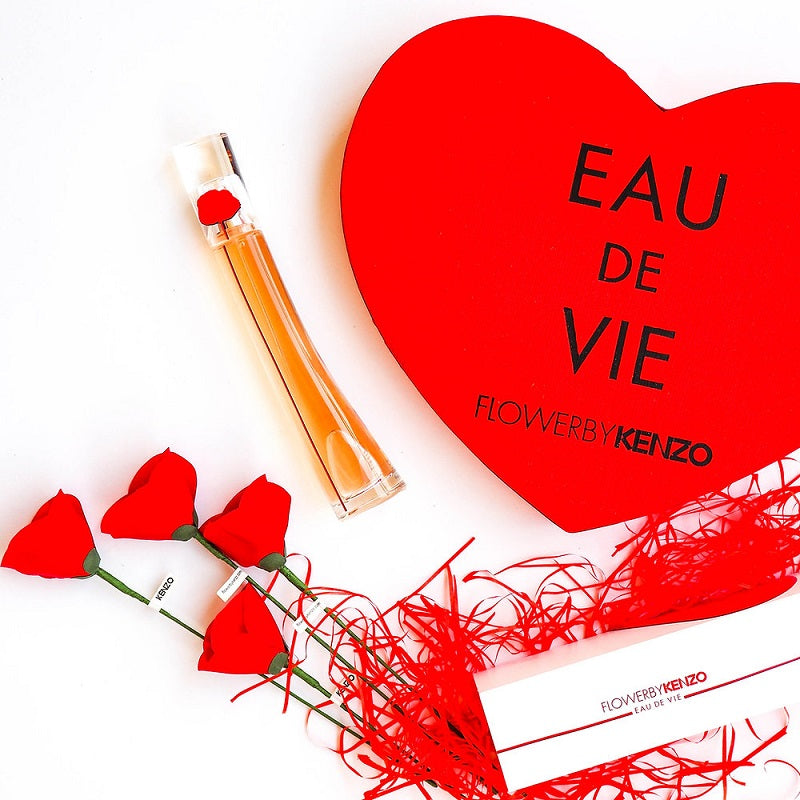 Perfume bottle with red heart-shaped box and flowers on a white background