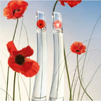 Two clear perfume bottles of 100nl Eau de Toilette perfume with red poppies against a blue sky.