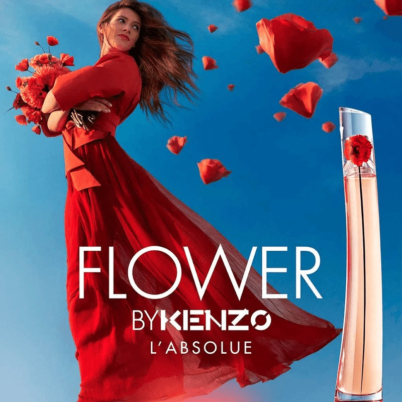 Advertisement for 'Flower by Kenzo L'Absolue' with a woman in a red dress and flying red flowers against a blue sky.