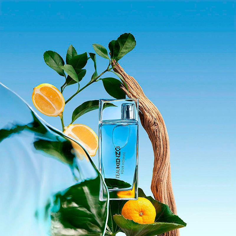 Kenzo perfume bottle with lemons and leaves on a blue background