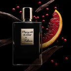 Perfume bottle labeled 'Playing with the Devil by Kilian' surrounded by fruits and spices on a dark background