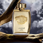Lalique perfume bottle with lion emblem on a branch against a cloudy sky