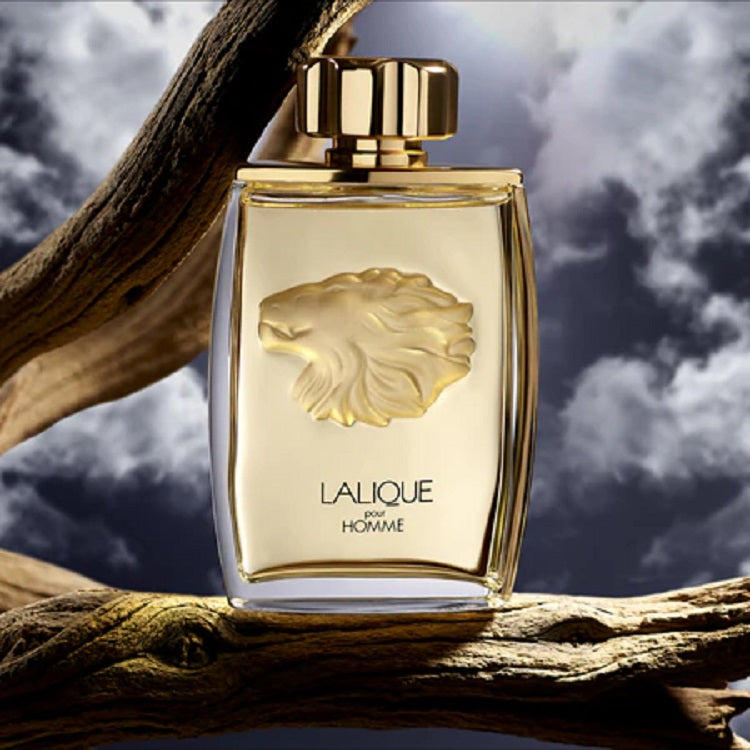 Lalique perfume bottle with lion emblem on a branch against a cloudy sky