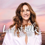 Woman with long brown hair wearing a white shirt against a pink sky with 'La vie est belle' text.