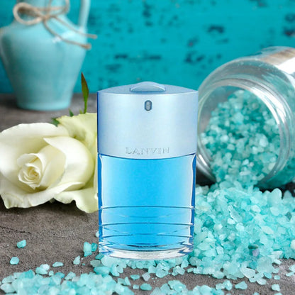 Blue Lanvin perfume bottle with white roses and turquoise stones on a textured surface.