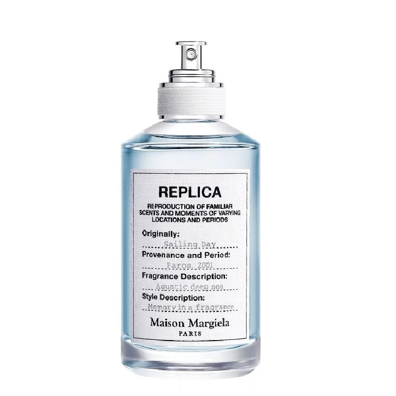 A transparent spray bottle of Maison Margiela Replica Sailing Day Eau de Toilette, with a white label and text.