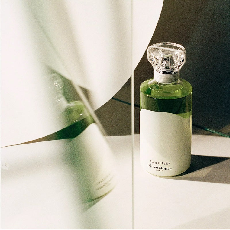 Green perfume bottle with a white label on a reflective surface