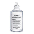 A spray bottle of Maison Margiela Lazy Sunday Morning Eau de Toilette, with a white label and text detailing the fragrance description.