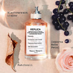 Perfume bottle labeled 'Replica' with blackcurrants and a rose on a textured background
