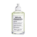 A spray bottle of Maison Margiela Replica Under the Lemon Trees Eau de Toilette, indicating the fragrance is a crisp citrus scent with notes of lime, green tea, and white musk.