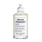 A spray bottle of Maison Margiela Replica Under the Lemon Trees Eau de Toilette, indicating the fragrance is a crisp citrus scent with notes of lime, green tea, and white musk.