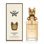 MCM Charming Pup Eau de Parfum bottle and packaging box. The bottle features a gold dog-shaped cap on a clear glass bottle filled with light amber liquid, next to its cream-colored box with brown borders and a black MCM logo.
